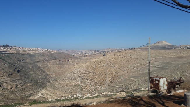 Vista norte desde la colonia Nokdim en el bloque Gush Etzion. La colonia Tekoa está a la izquierda. Al centro en primer plano hay una cámara de seguridad; al fondo a la derecha, el Herodium.