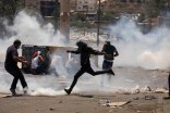 Jóvenes de Beita patean los cartuchos de gas lacrimógeno durante una protesta contra la colonia Evyatar.